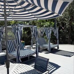 Relax and unwind poolside lounge chairs on a deck next to a table with chairs and an umbrella